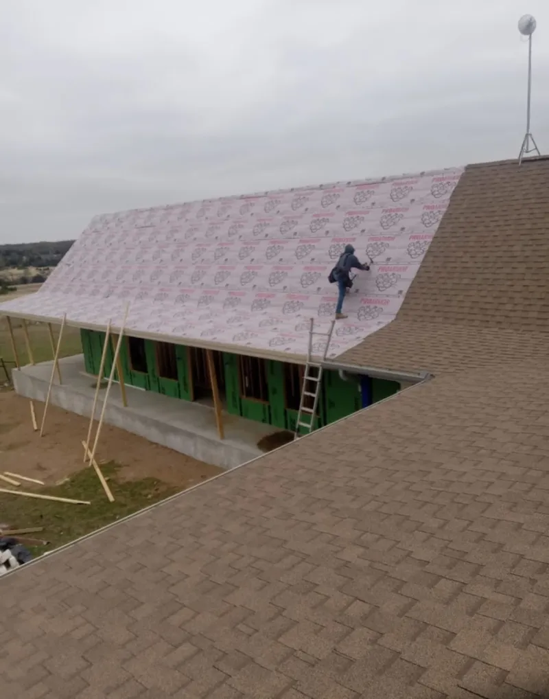 Worker preparing underlayment for a metal roof installation in Tumwater